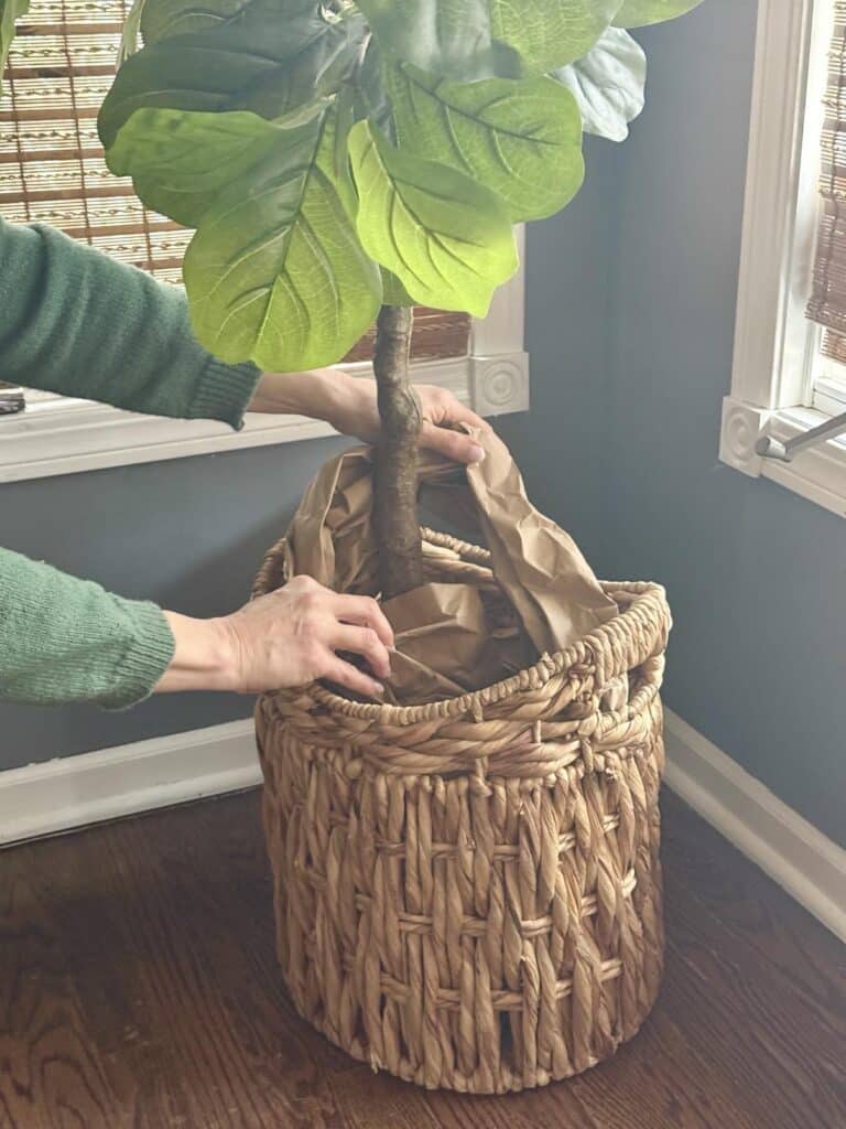 Stuffing a basket with paper for decorating with faux plants.