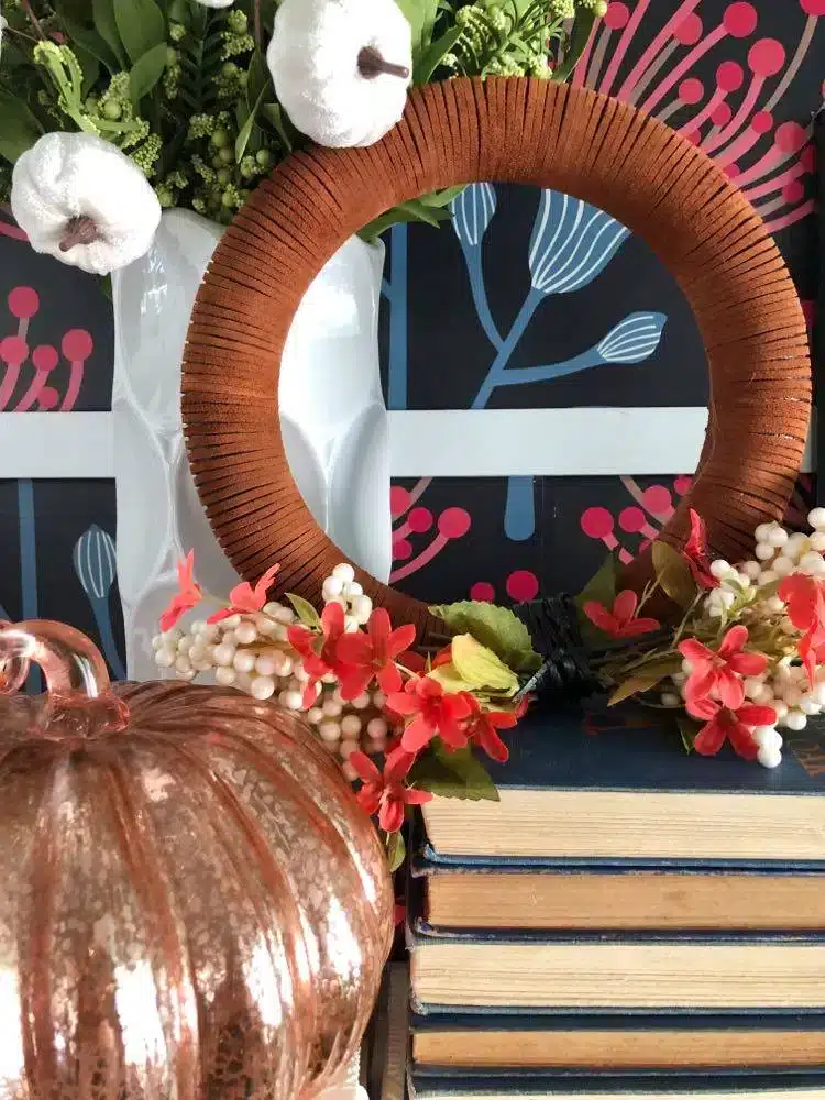 A diy fall wreath on a bookshelf.