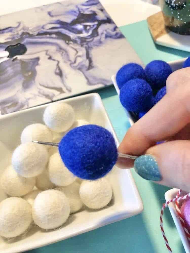 A needle piercing a blue wool ball.