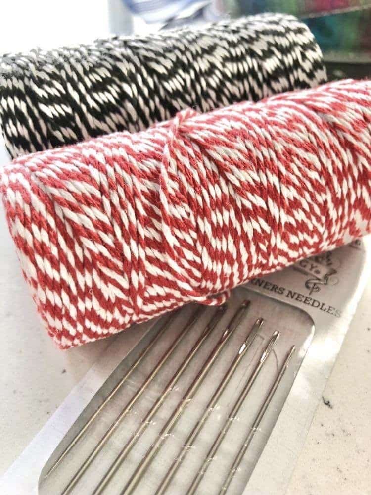 Red and white stripe twine and a packet of needles.