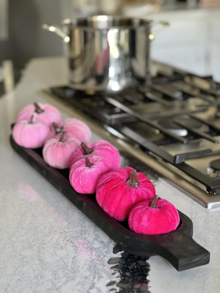 Bright pink velvet pumpkins decorating aa black dough bowl.