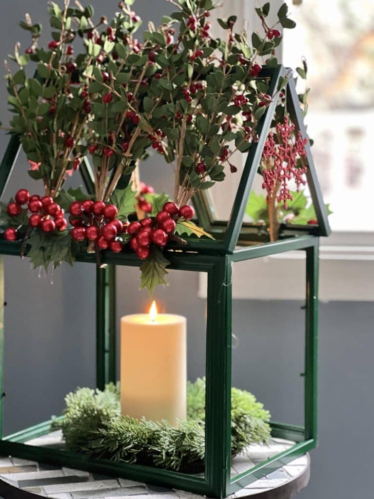 A DIY tabletop greenhouse with a pillar candle in the center.