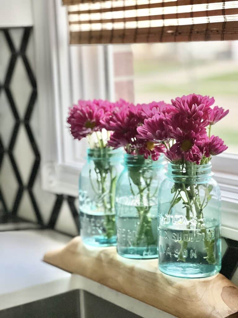 https://www.sonatahomedesign.com/wp-content/uploads/2023/04/Purple-Flowers-in-Blue-Glass-Mason-Jars-Sonata-Home-Design-768x1024.jpg