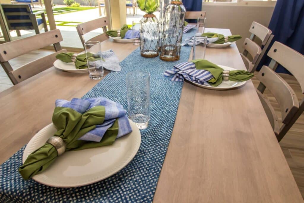 A blue textured cotton table runner decorating a wood table.