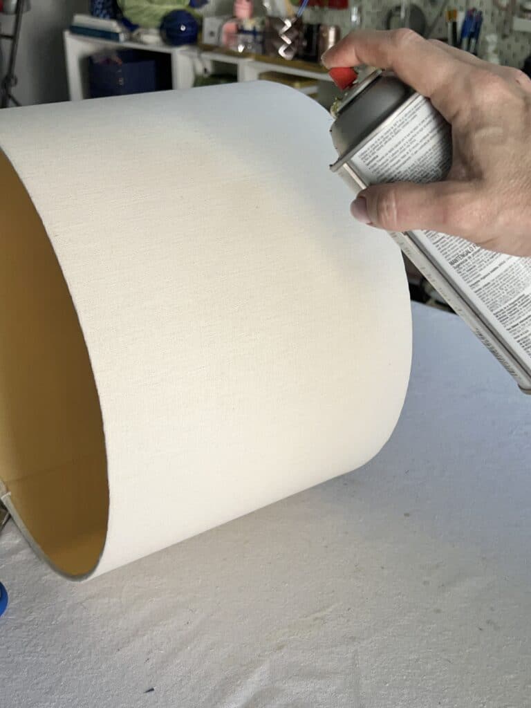 Applying spray adhesive to the outside of the old lamp shade.
