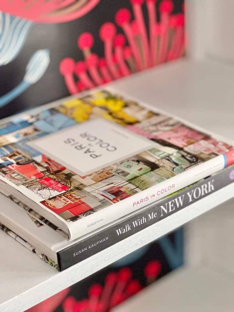 Colorful coffee table books about Paris and New York decorating a bookshelf.