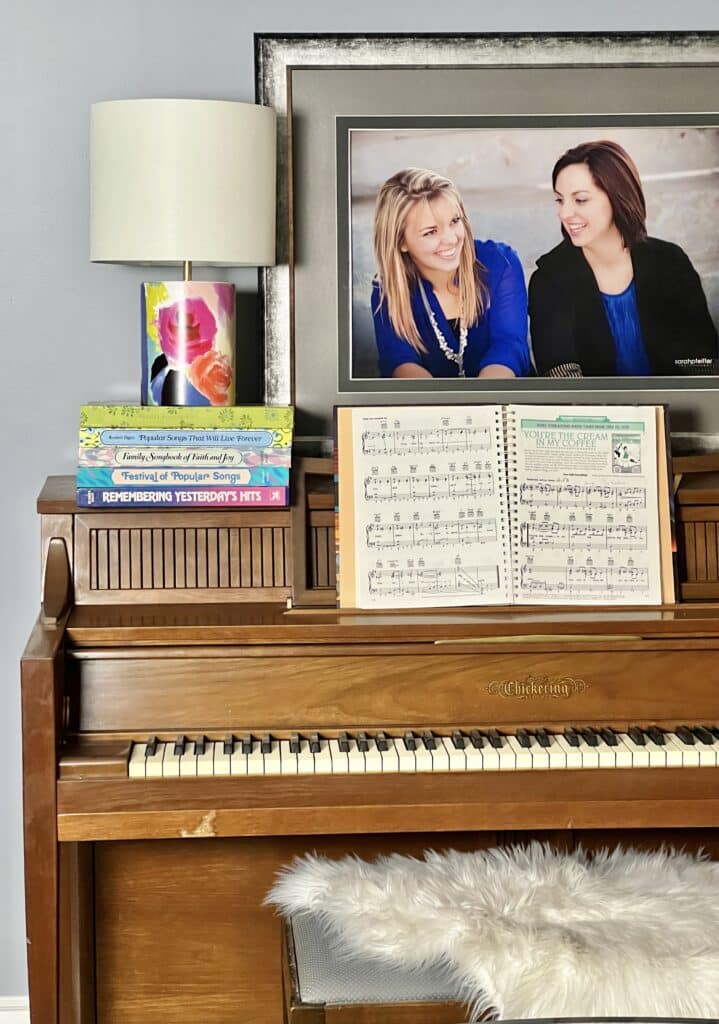 piano decorating ideas: an upright piano decorate with stacks of music books and a lamp.