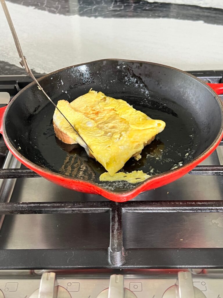 Eggs folded onto bread for one pan egg sandwich.