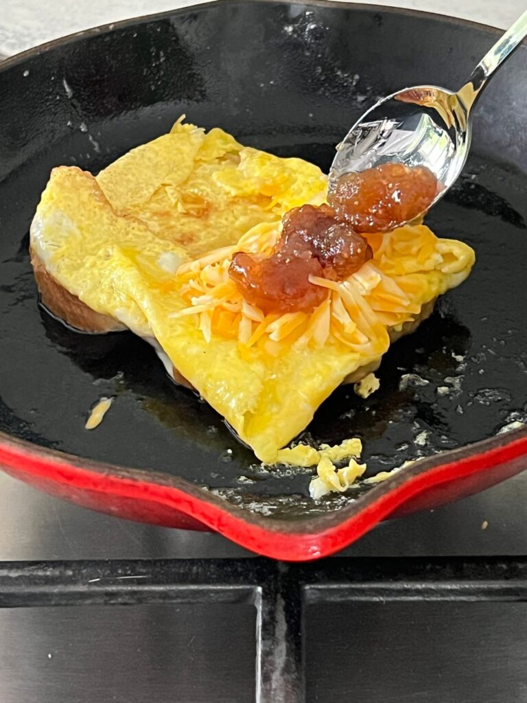 Spooning fig preserves on top of cheese and egg.