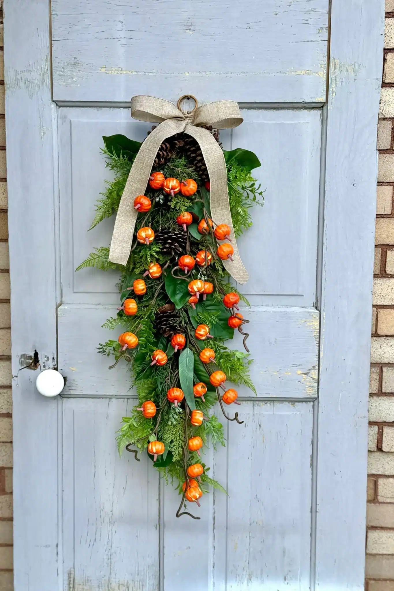 A pumpkin and greenery Fall swag for the front porch door.