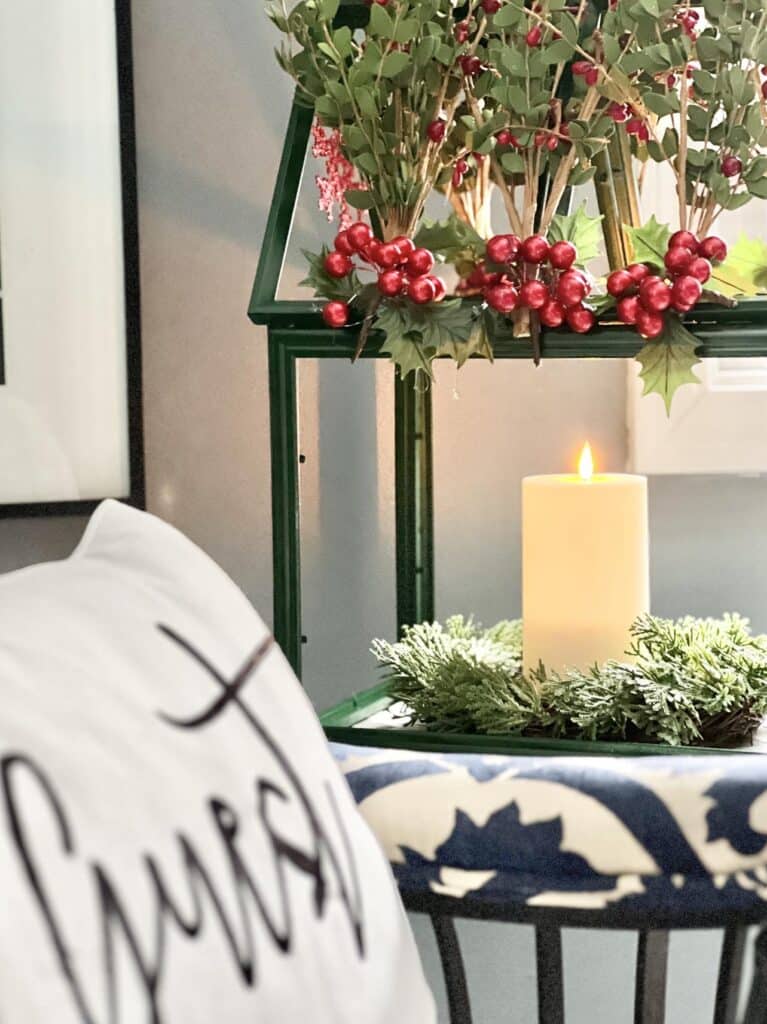 A tabletop greenhouse with a faux candle and red berries.