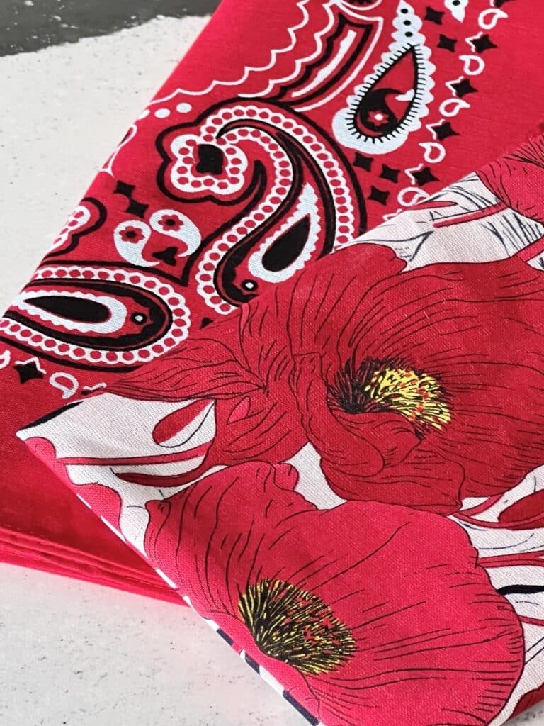 Two bandana: One in a traditional red western pattern and one in a red poppy floral pattern.