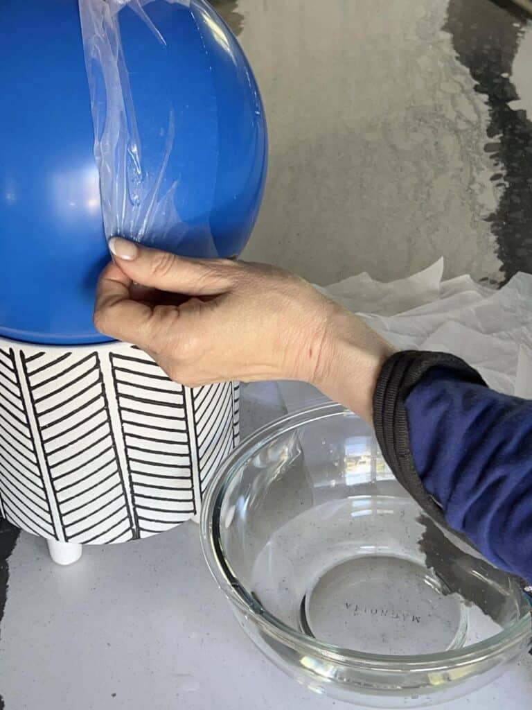 Applying a wet sheet of tissue paper to a blown up balloon.