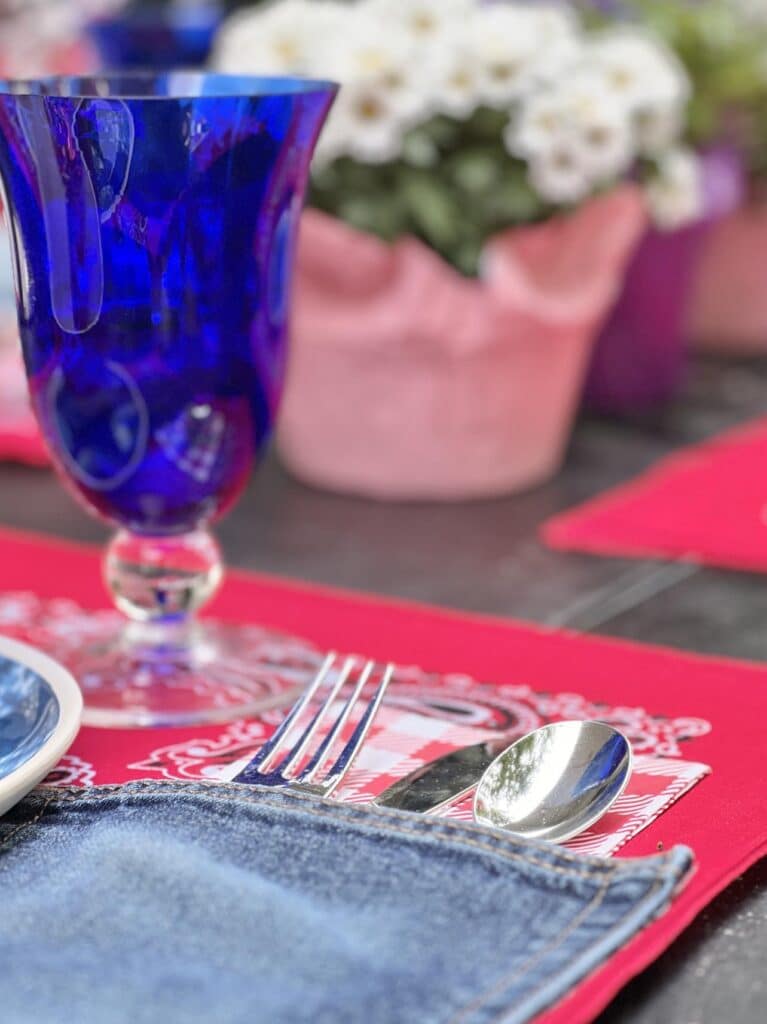 A denim pocket on the placemat full of silverware.