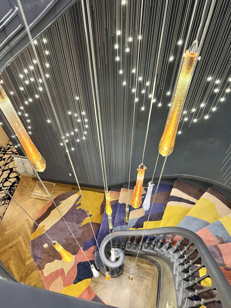 Spiral staircase with dangling lights lead Show Home visitors to each floor of the Kips Bay home.
