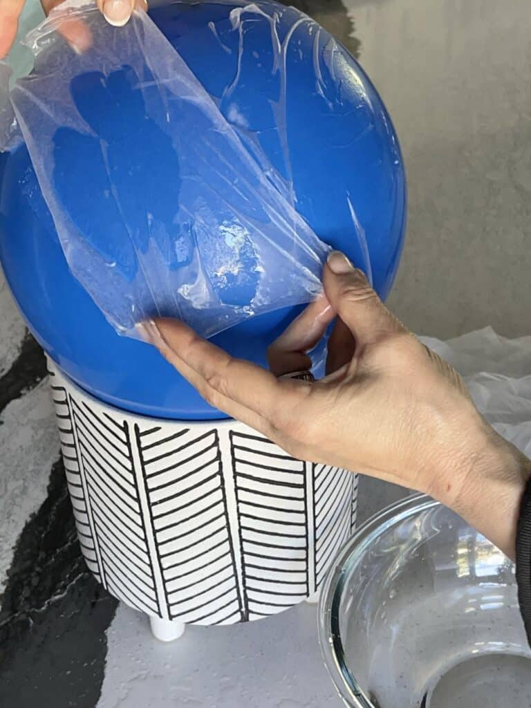 Layering wet tissue paper sheets onto a balloon.