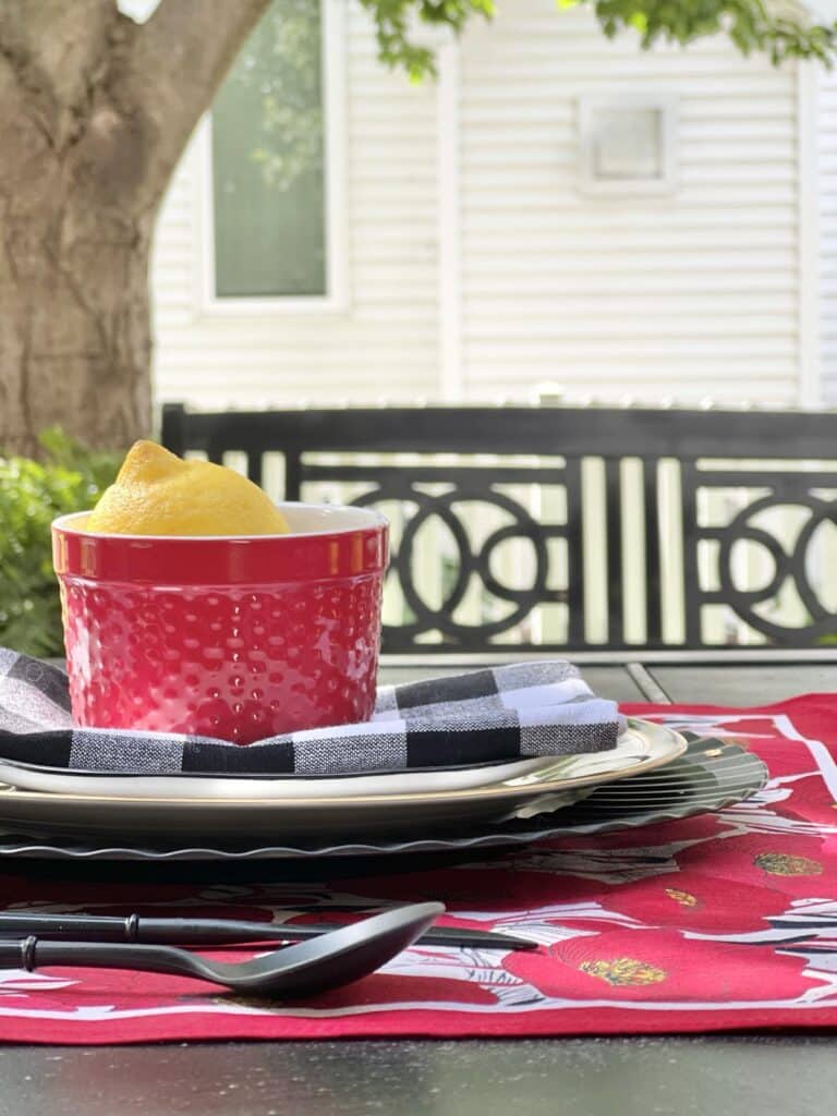 a red ramekin siting on top of aa reversible diy placemat made from bandanas.