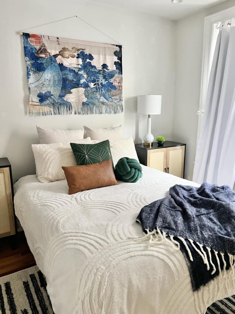 A bed with white comforter and a spring tapestry decoration on the wall.