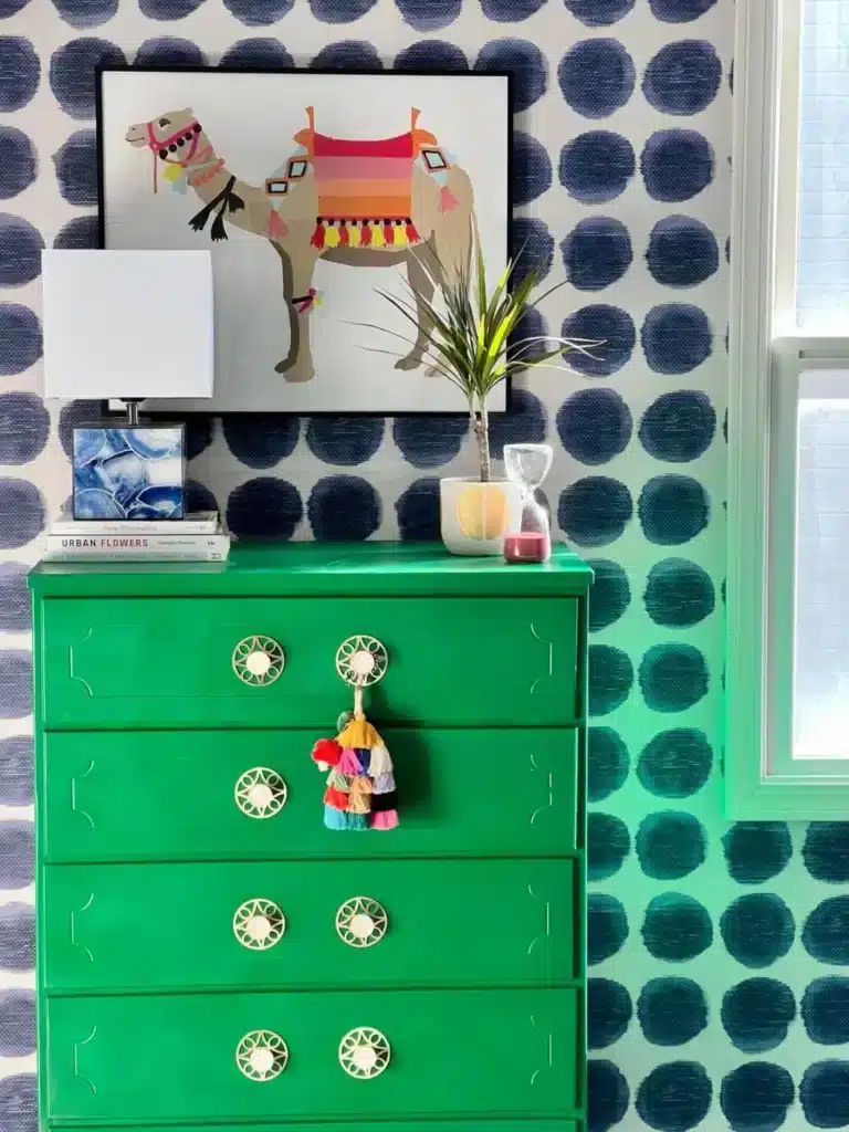 A green dresser with brass knob handles.