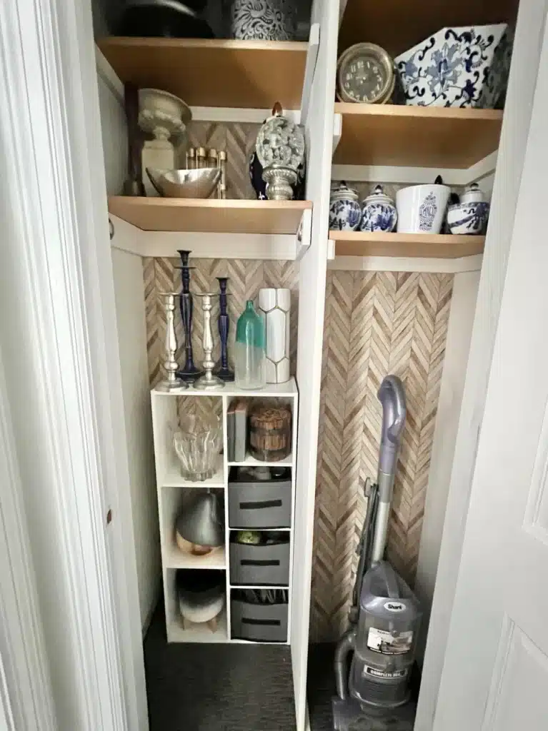 A closet reorganized and decorated with wallpaper sheets in an ivory and brown chevron pattern.