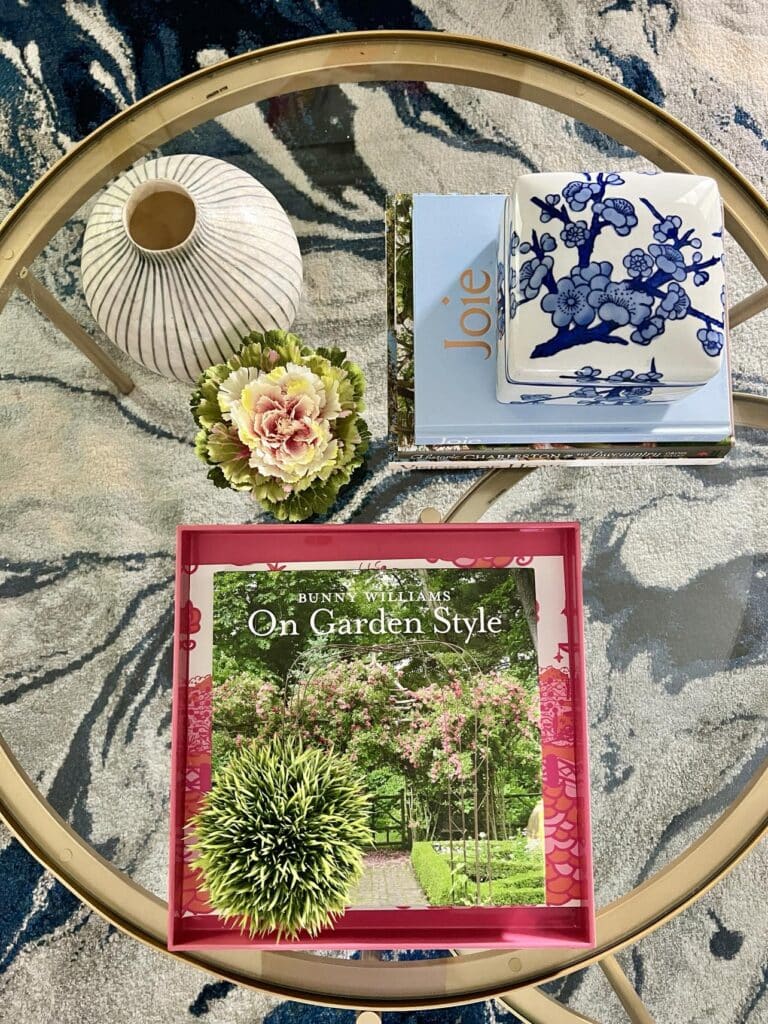 A coffee table styled with books, a vase, and faux flowers.