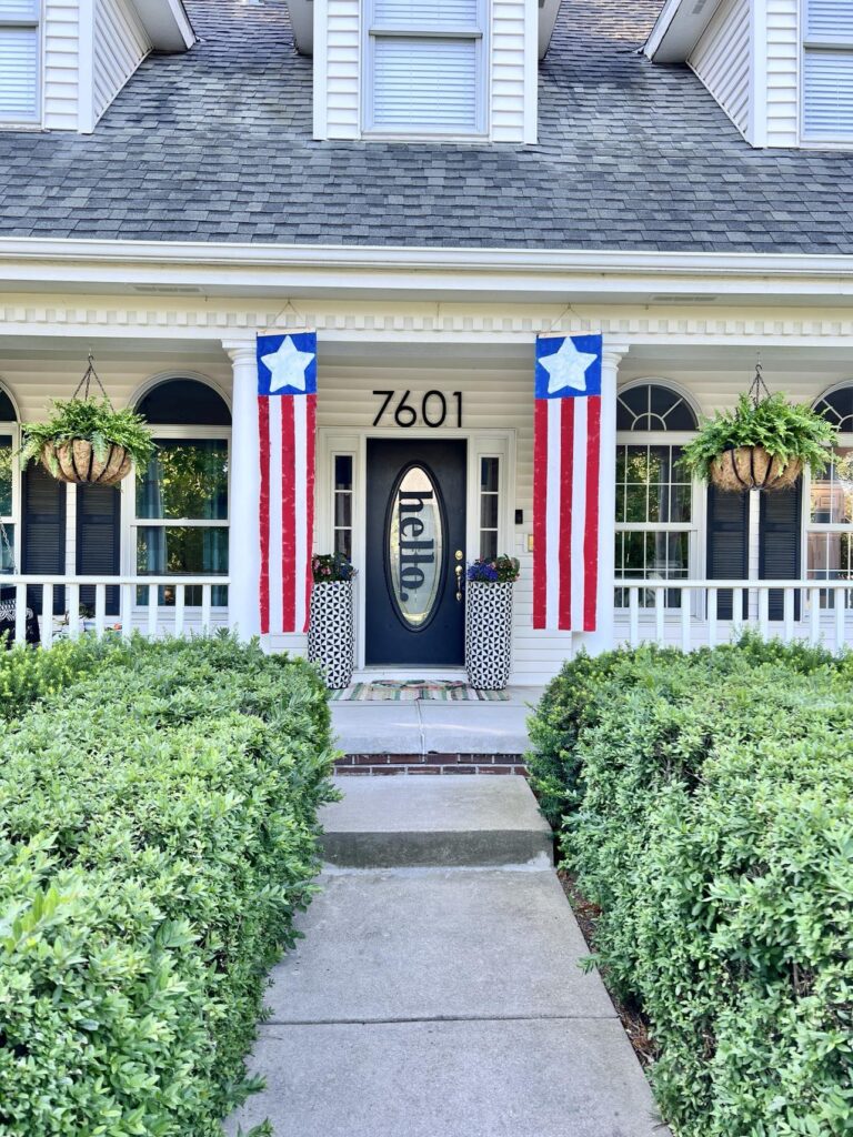Two DIY Fabric Banners hanging on the front of a white house porch.