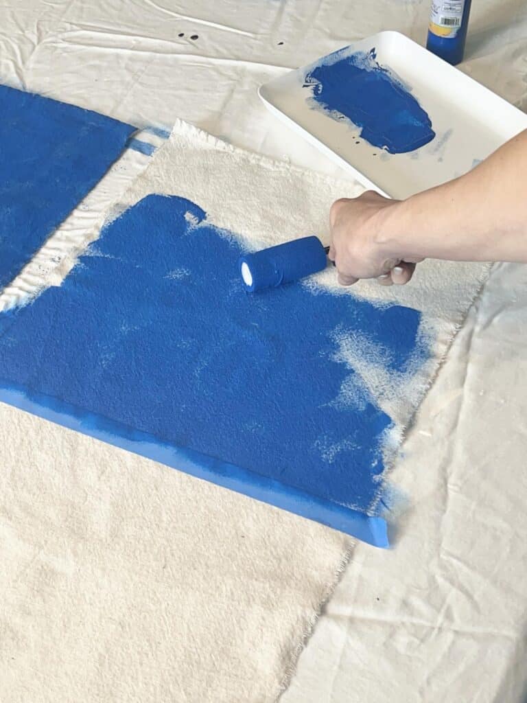 Rolling blue paint onto the top box of the DIY Flag Banner.