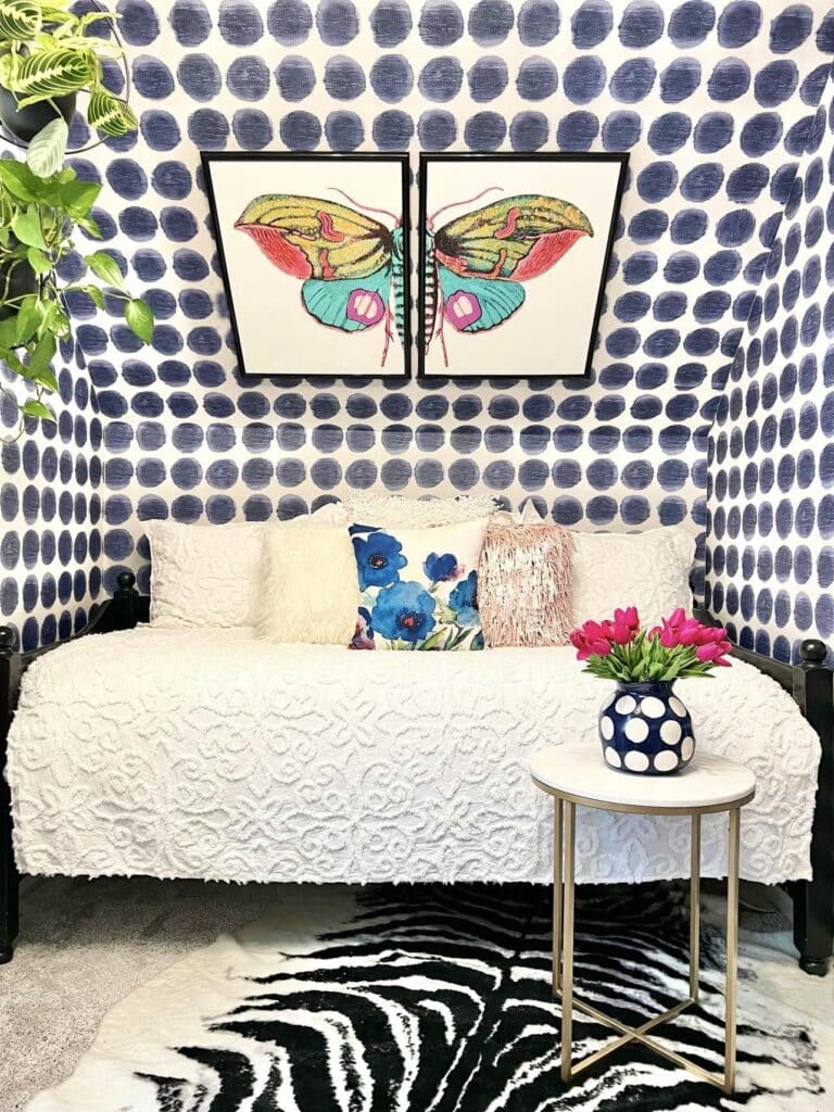 A daybed sitting in front of a wall with blue and white polka dot wallpaper.