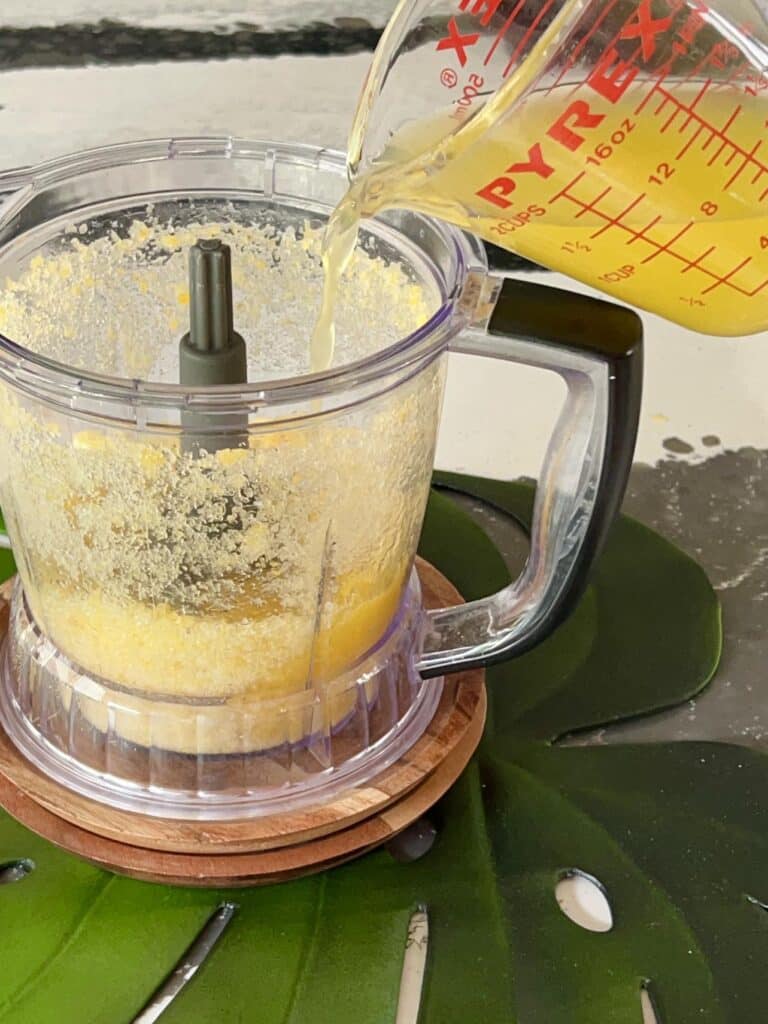 Adding pineapple mango juice to food processor.