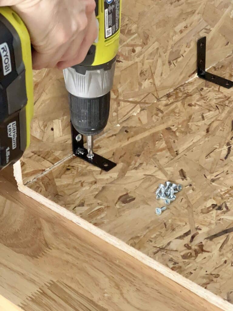 Securing brackets against wood with a drill.