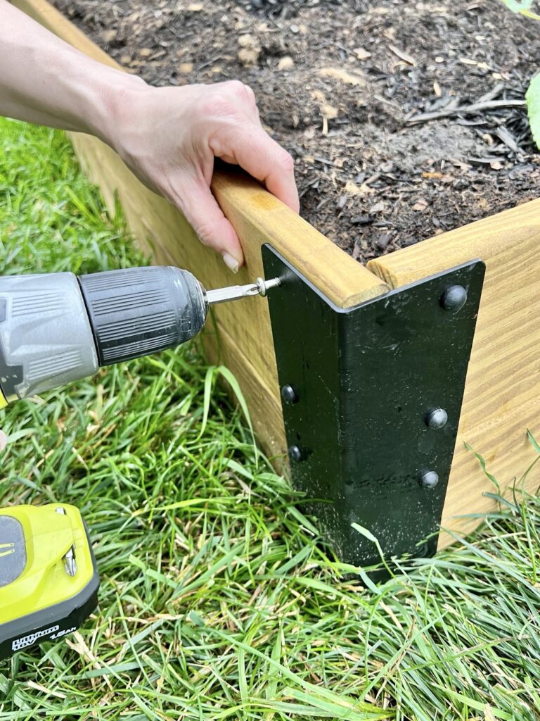 Using a drill to screw together a Toja Grid corner bracket to construct and easy raised garden bed.