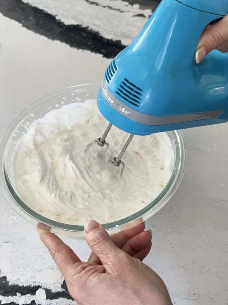 Beating whipping cream with a handheld mixer.