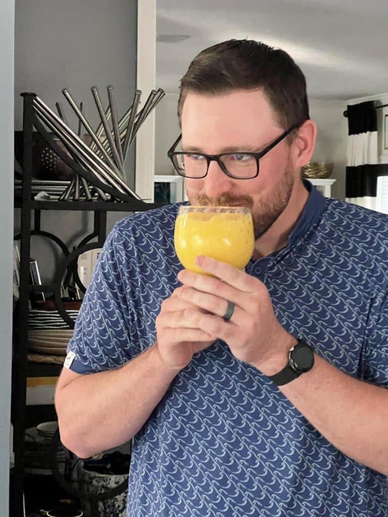 Man with beard drinking a mango a go go smoothie.