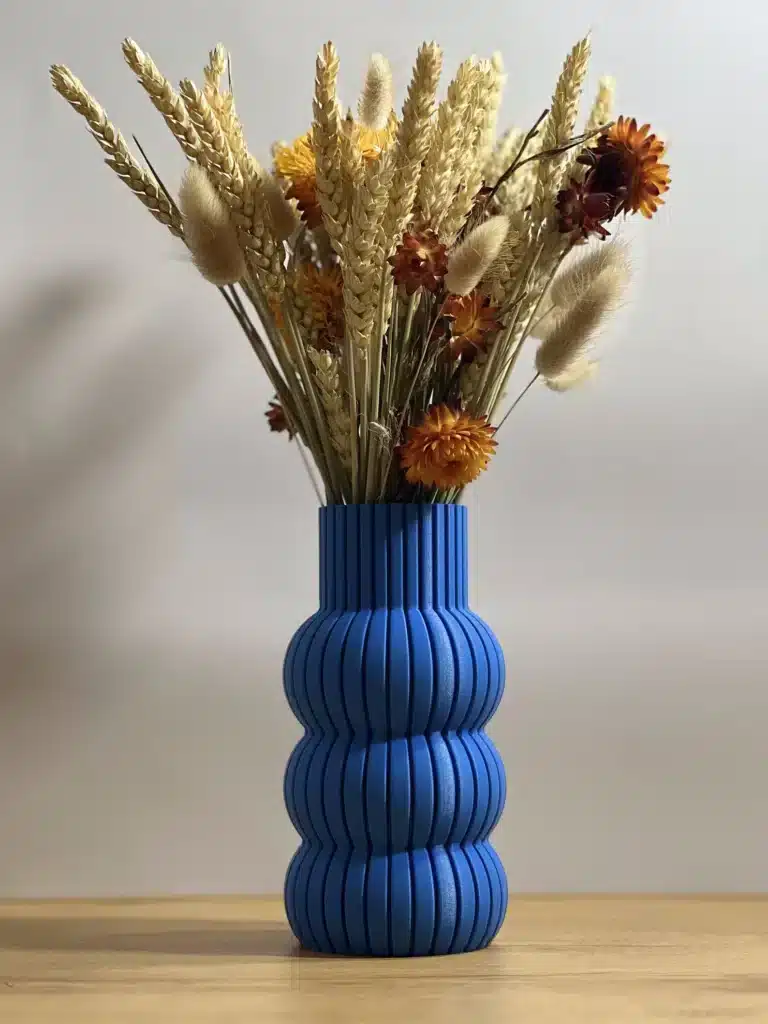 A cobalt blue vase full of dried flowers.