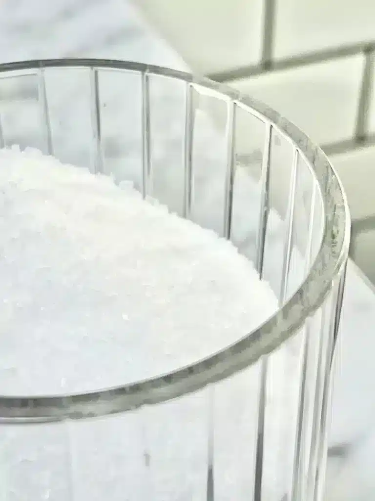 A cut glass jar filled with white epsom salts.