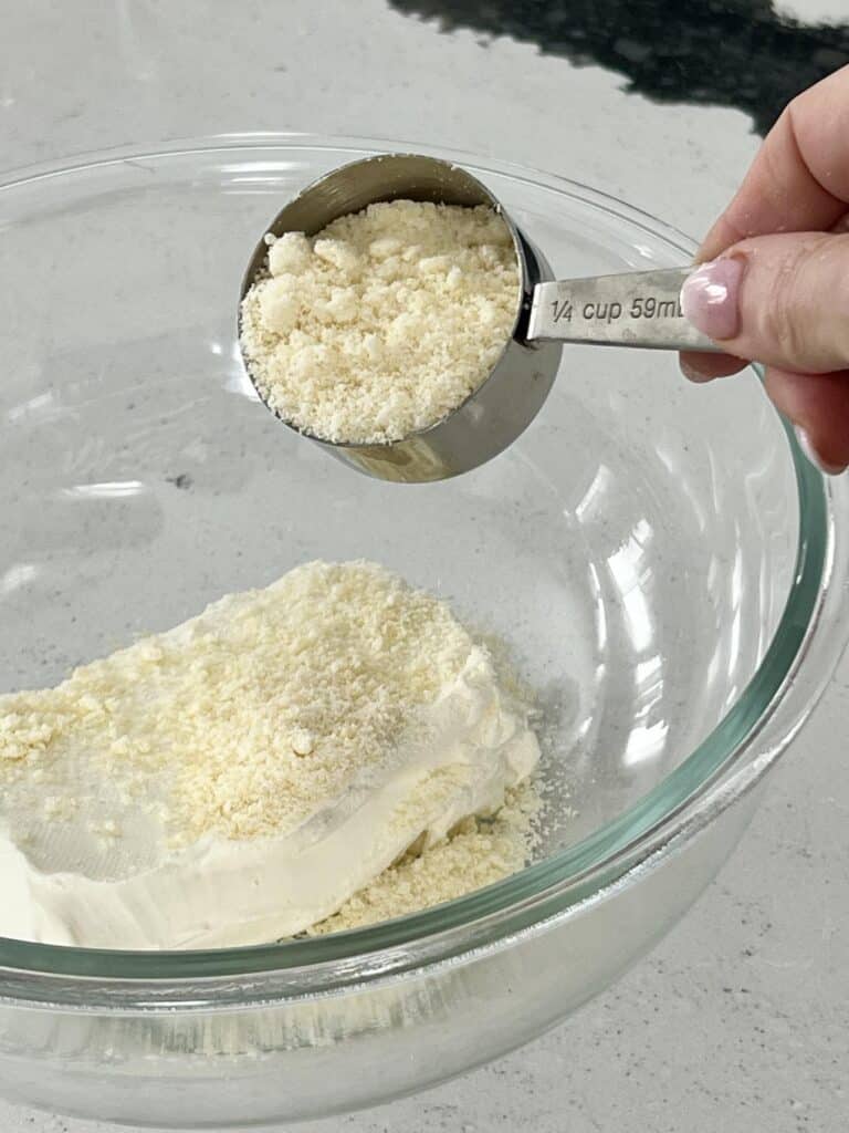 Mixing Parmesan and Romano cheeses together in a glass bowl.