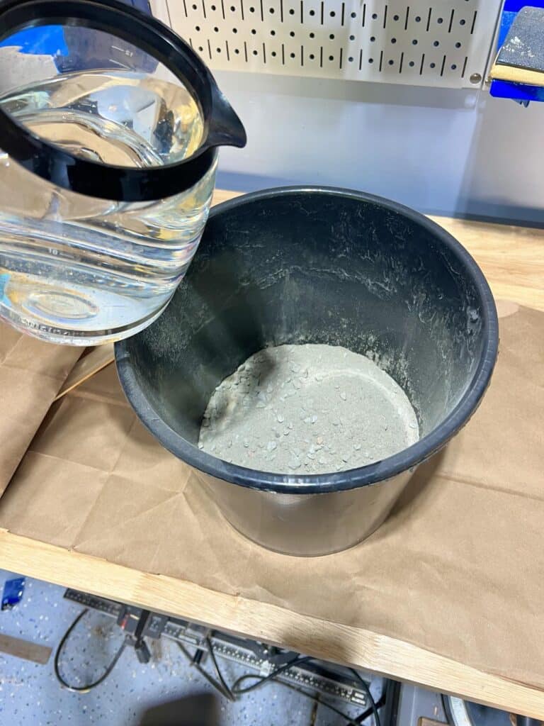 Pouring water into concrete mix for a DIY bowl.