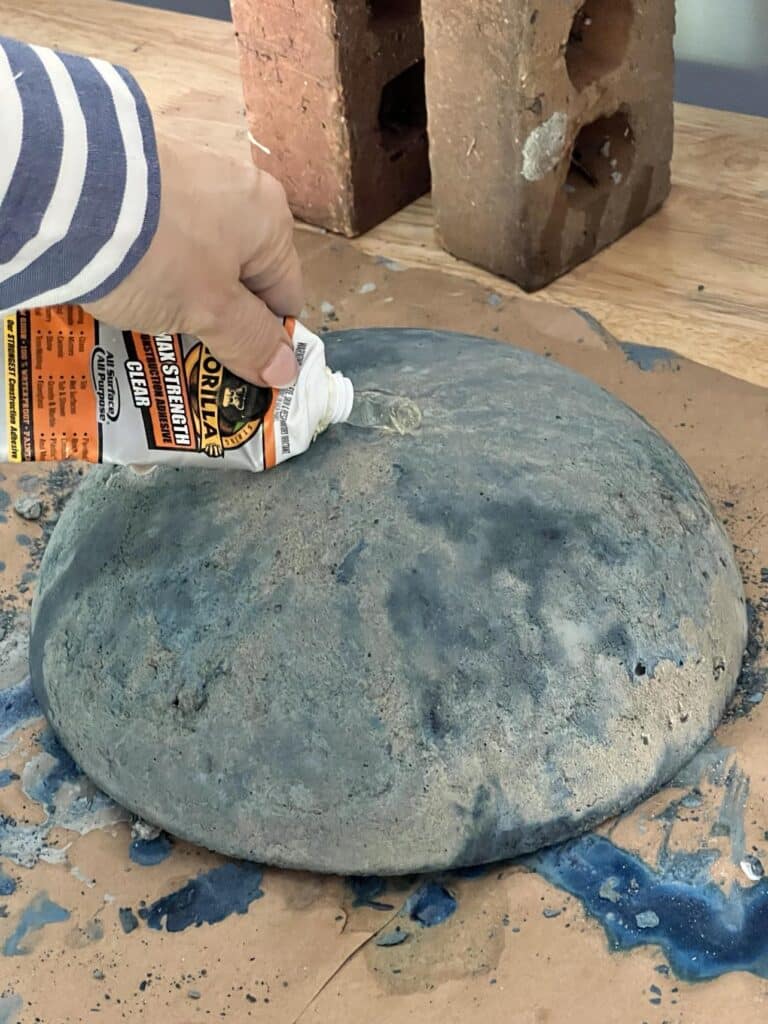 Squeezing Gorilla glue to the rounded top of the concrete bowl base.