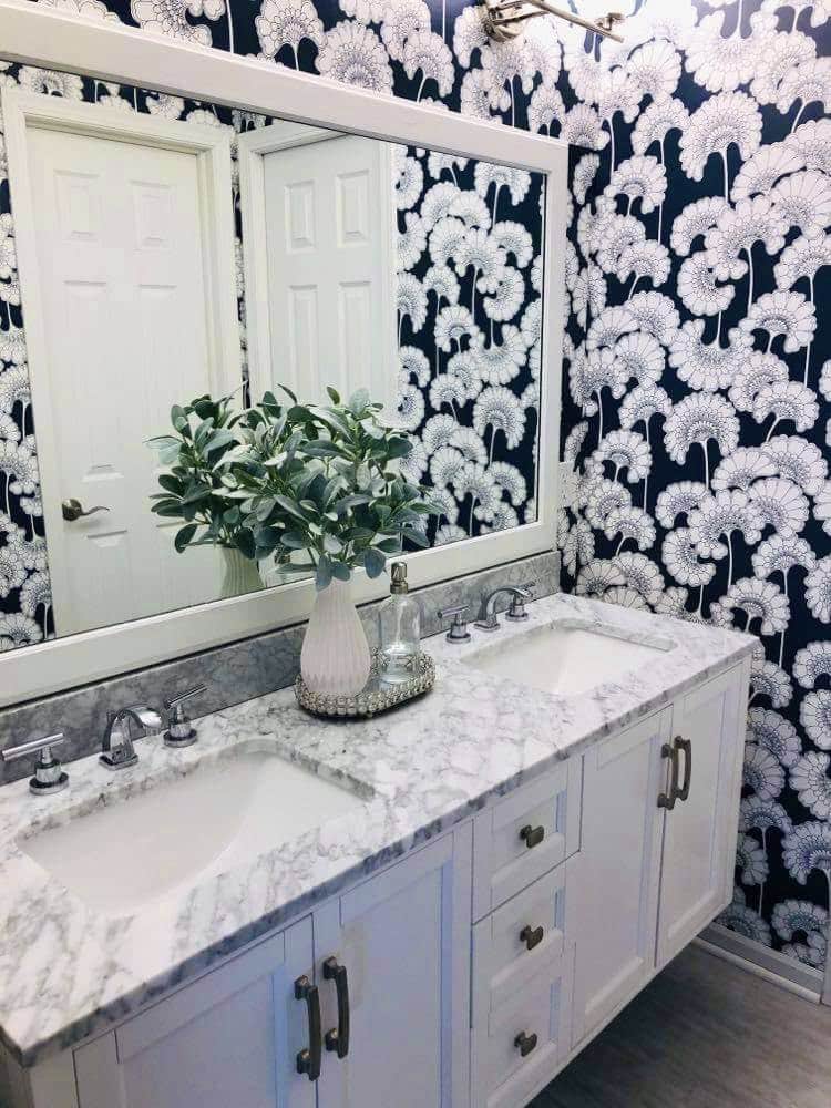 A small tray holding a vase with floral stems, and a hand sanitizer bottle sitting on a bathroom countertop.