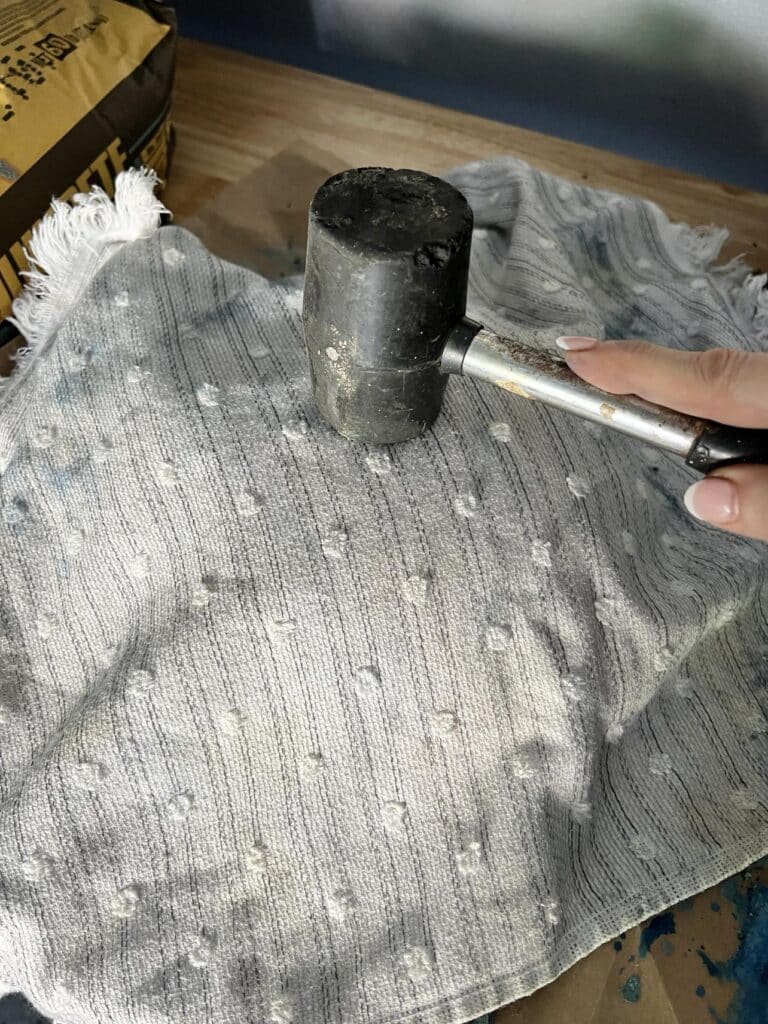 Breaking the glass of concrete bowl form with a towel and a rubber mallet.