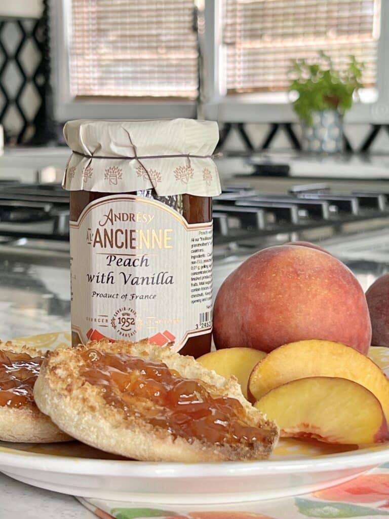 A jar of peach jam, fresh peaches, and fresh English muffins can be considered little luxuries for breakfast.