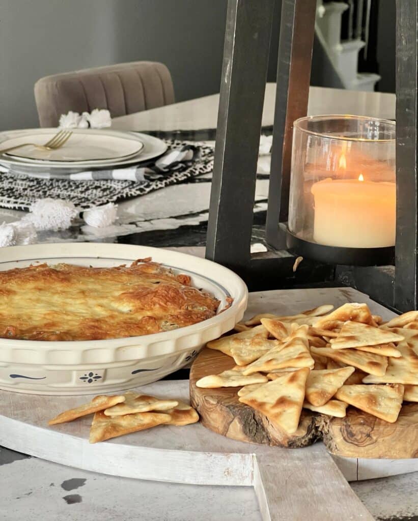 A baked spinach artichoke dip on a table with pita chips.