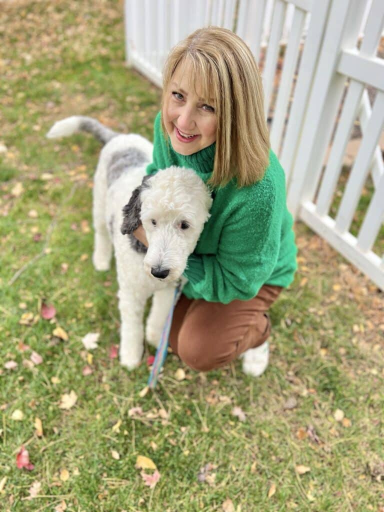 Woman in a green sweater with a white dog.