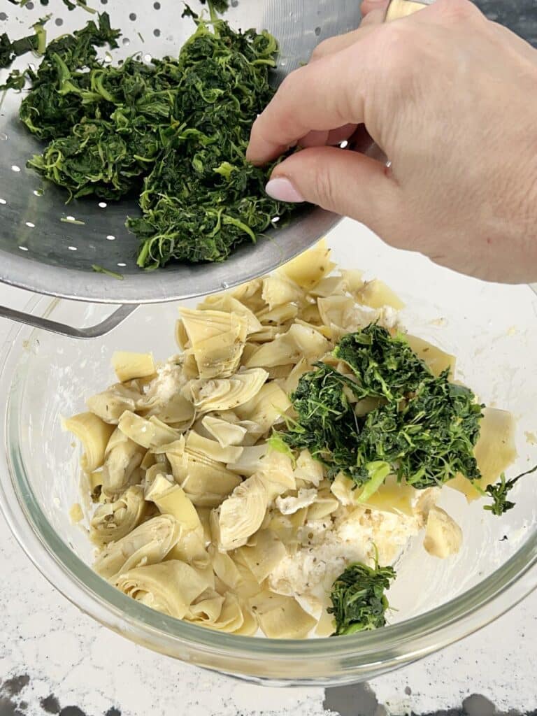 Mixing frozen spinach with artichoke hearts.