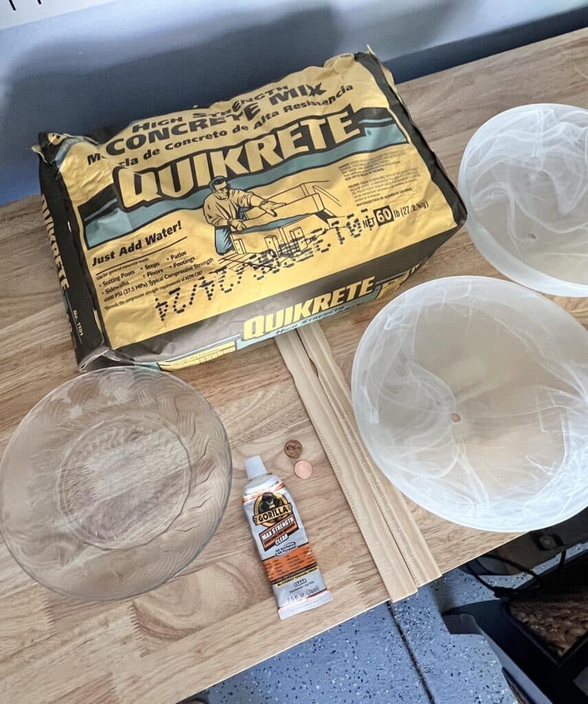 A bag of concrete mix, glass light fixture cover bowls, and a glass plate.