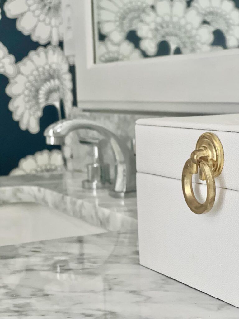 A white box with a gold handle used as countertop decor in the bathroom.