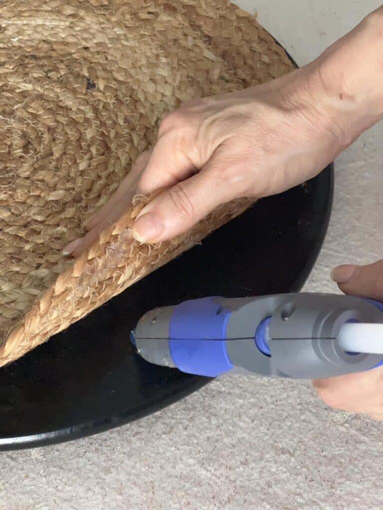 Gluing a woven placemat to the top of a lazy Susan for a decorative DIY hack.