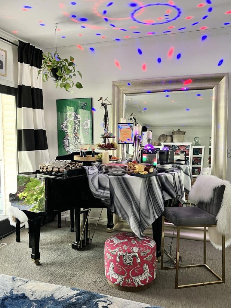 A baby grand piano decorated for a karaoke party with food and multi colored lights.