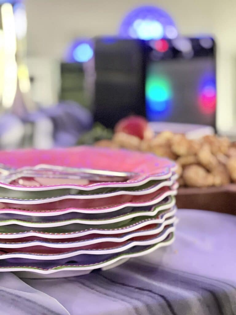 A stack of multi colored plates in front of a light karaoke party machine.