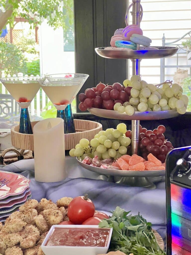 A tiered tray full of grapes and macarons for a karaoke party.